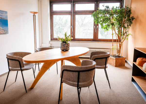 Beratungsraum im Kundentreffpunkt mit ovalem Holztisch, Sesseln, Pflanzen